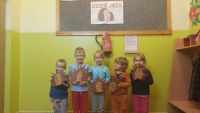 Niewielka grupka dzieci stoi przed plakatem Dzień jeża, a w ręku trzymają własnoręcznie wykonane jeże z rolki po papierze...