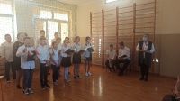 Uczniowie odświętnie ubrani śpiewają hymn