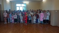 Grupa dzieci  i nauczycieli w piżamach w sali gimnastycznej